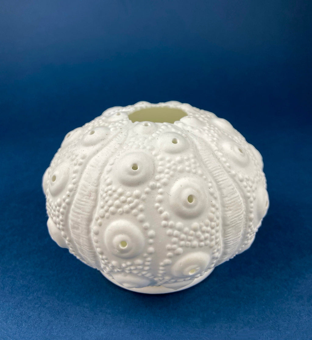 White ceramic bulb-shaped container with embossed circular pattern and small holes.