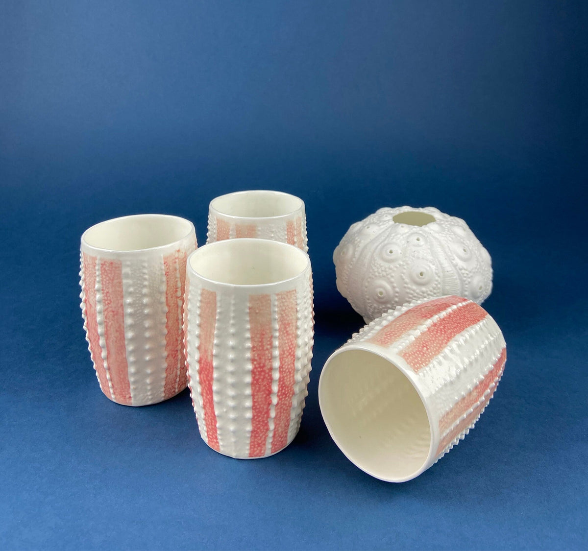Porcelain mugs with pink striped pattern and raised texture, plus white embossed dome.