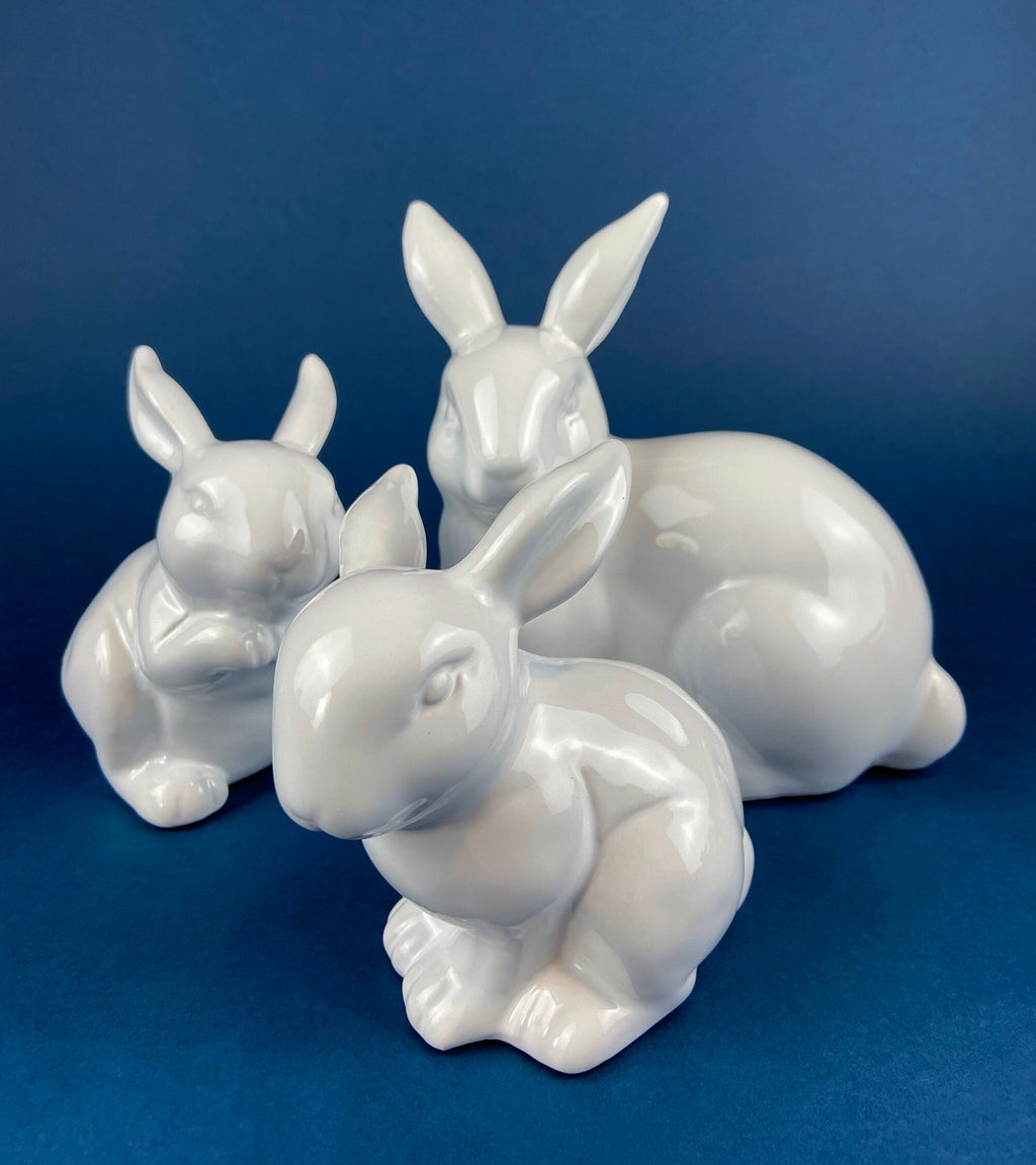 Set of white ceramic bunny figurines clustered together on a shared base