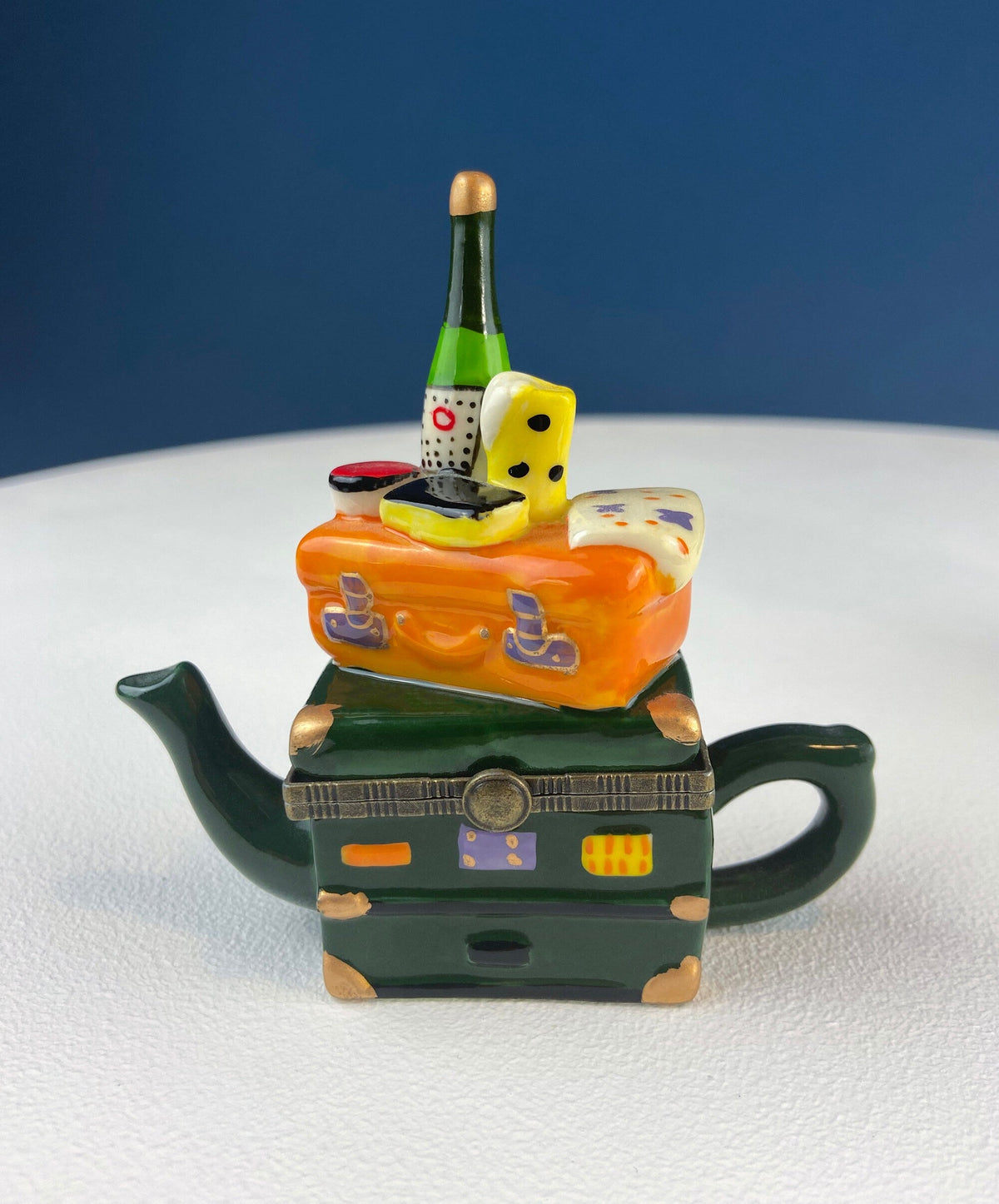Miniature porcelain pill box shaped like an orange teapot car, green handle