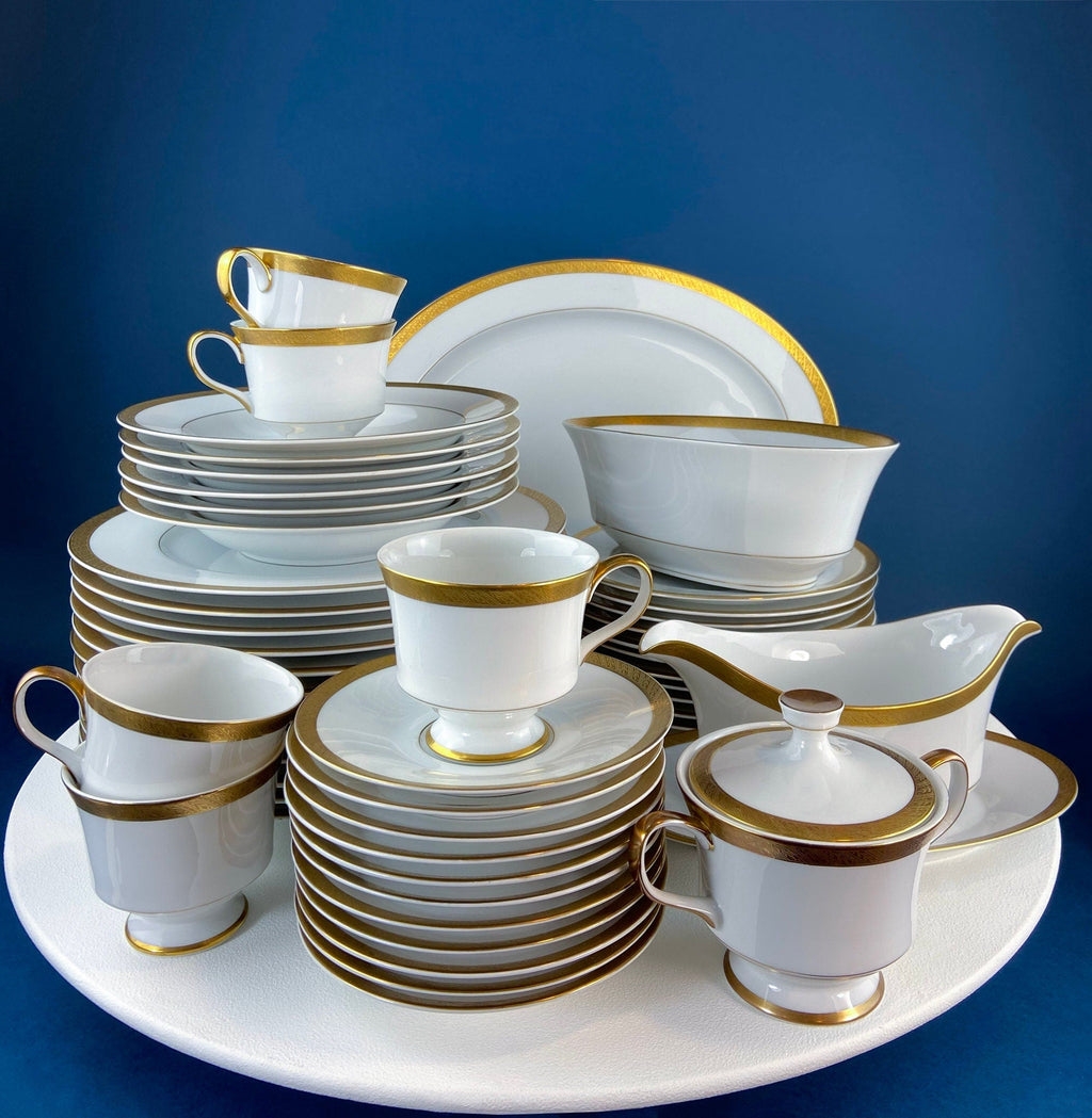 White porcelain serving set with gold rims and stacked dishes
