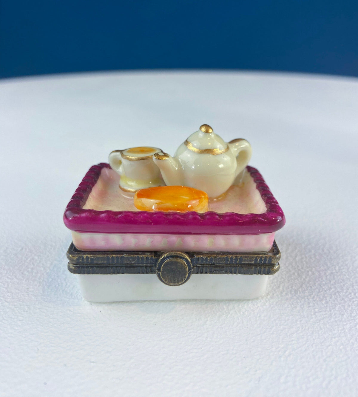 Miniature porcelain pill box with teapot and teacups on a purple tray