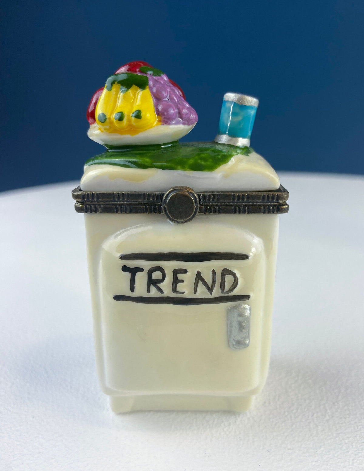 Miniature porcelain pill box with Trend text and blue bottle on green base