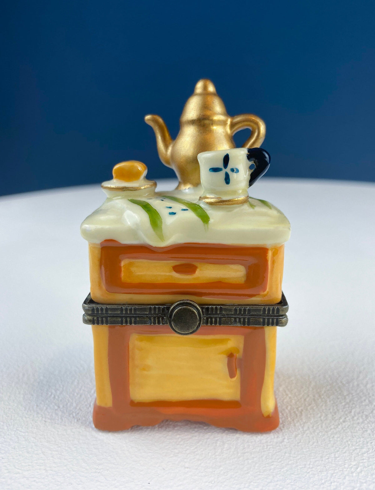 Miniature porcelain pill box with gold teapot and orange drawer base