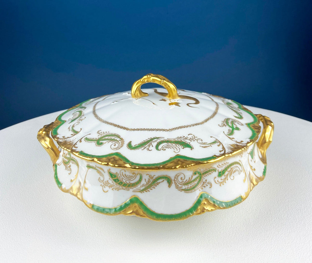 White porcelain tureen with green and gold ornamental trim and raised lid handle