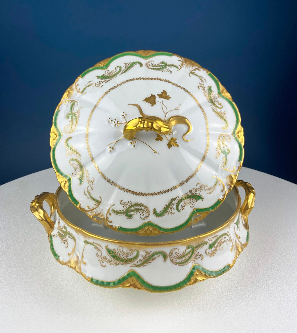 White porcelain tureen lid with green scroll accents, gold trim, and central decorative crest