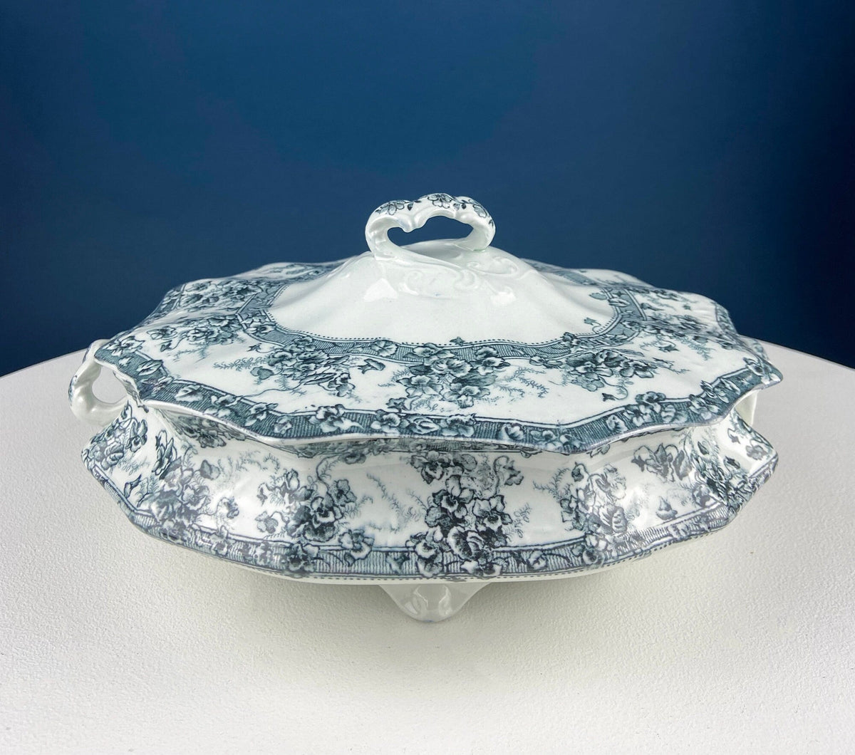 Blue and white porcelain serving tureen with ornate lid handle and floral scroll pattern