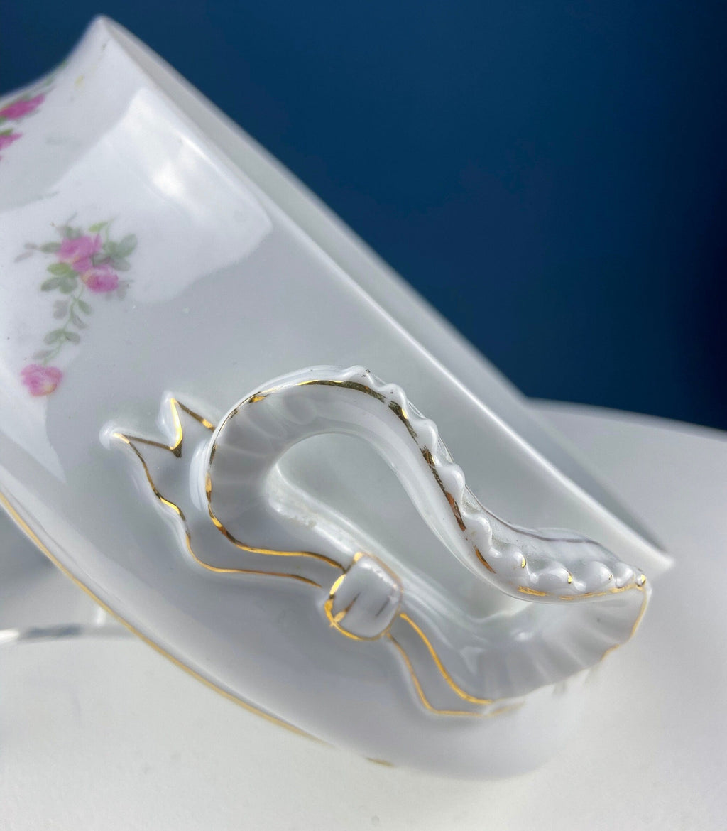 Porcelain tureen side detail with gold trim and curved bow-shaped handle