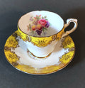 Yellow and gold porcelain tea cup and saucer set with pink fruit and floral bouquet