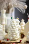 White Christmas tree soy candle on wooden base with small red and green ornaments
