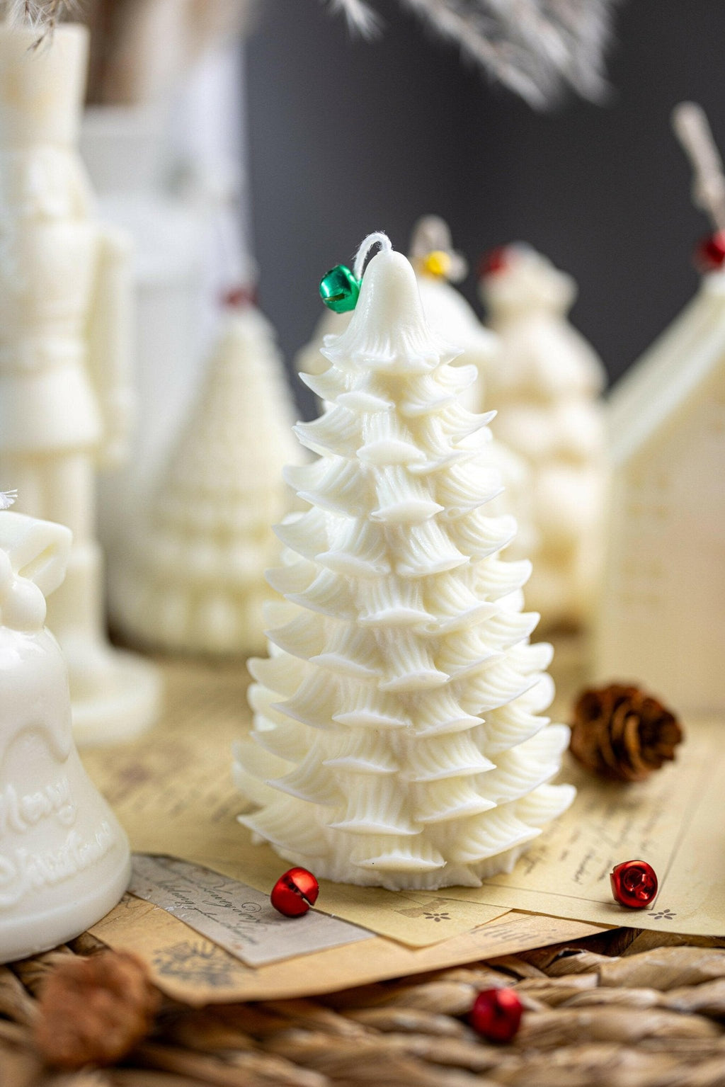 White Christmas tree candle with layered ridges, on wooden base with red and green baubles