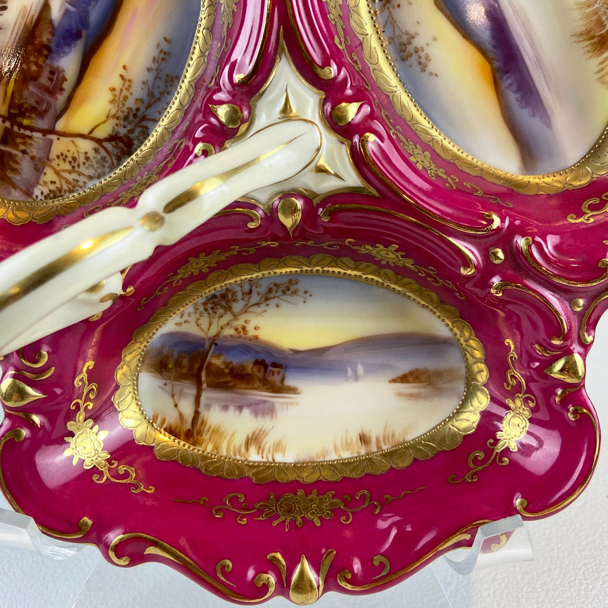 Porcelain divided serving bowl close-up, magenta enamel, gold scrollwork, central landscape