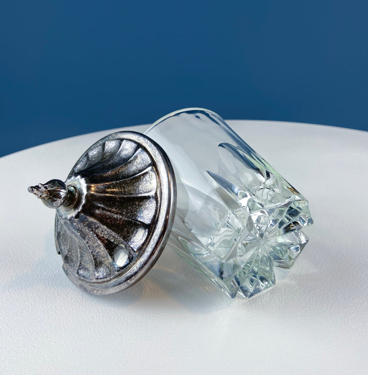 Clear glass jar with silver plated lid featuring hinged handle detail