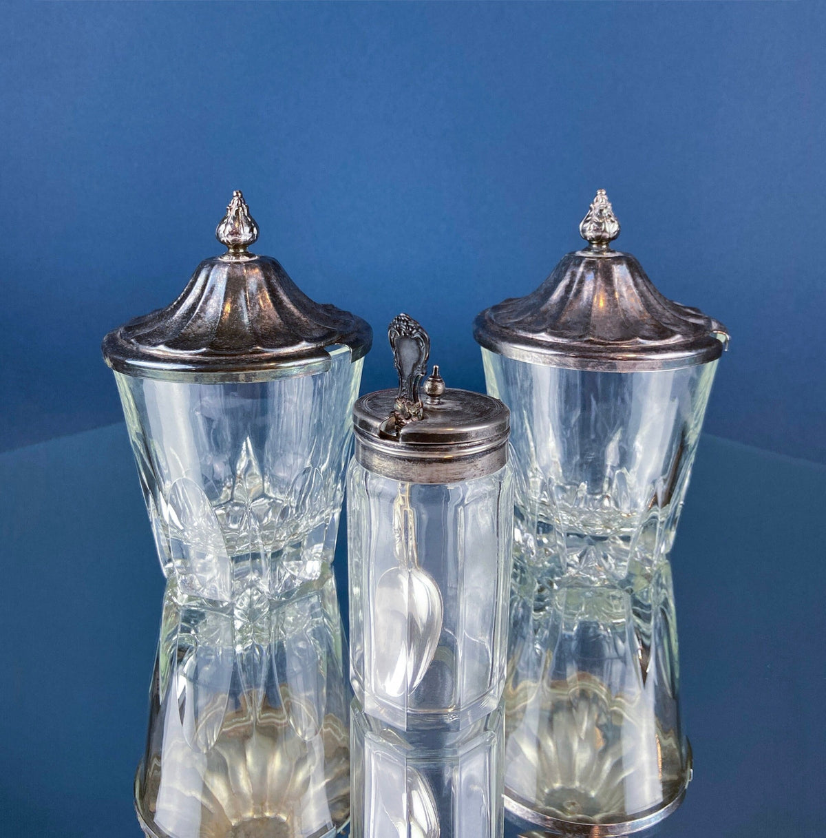 Clear glass condiment jars with ornate silver plated lids and finial, set of 3