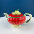 Red poppy-shaped ceramic teapot with green lid and yellow bee figurine