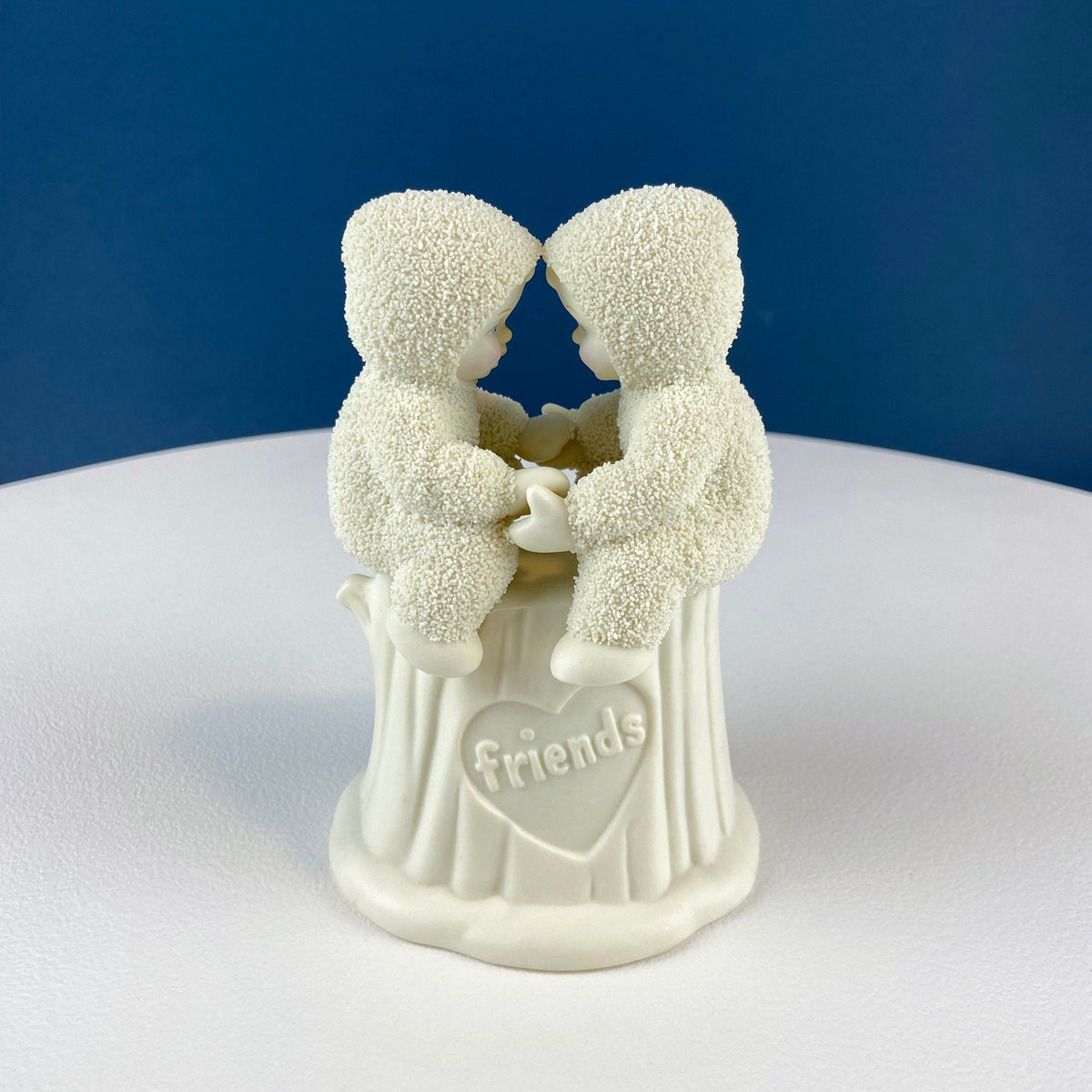 White porcelain snowbaby figurine with two kids hugging and a 'Friends' plaque