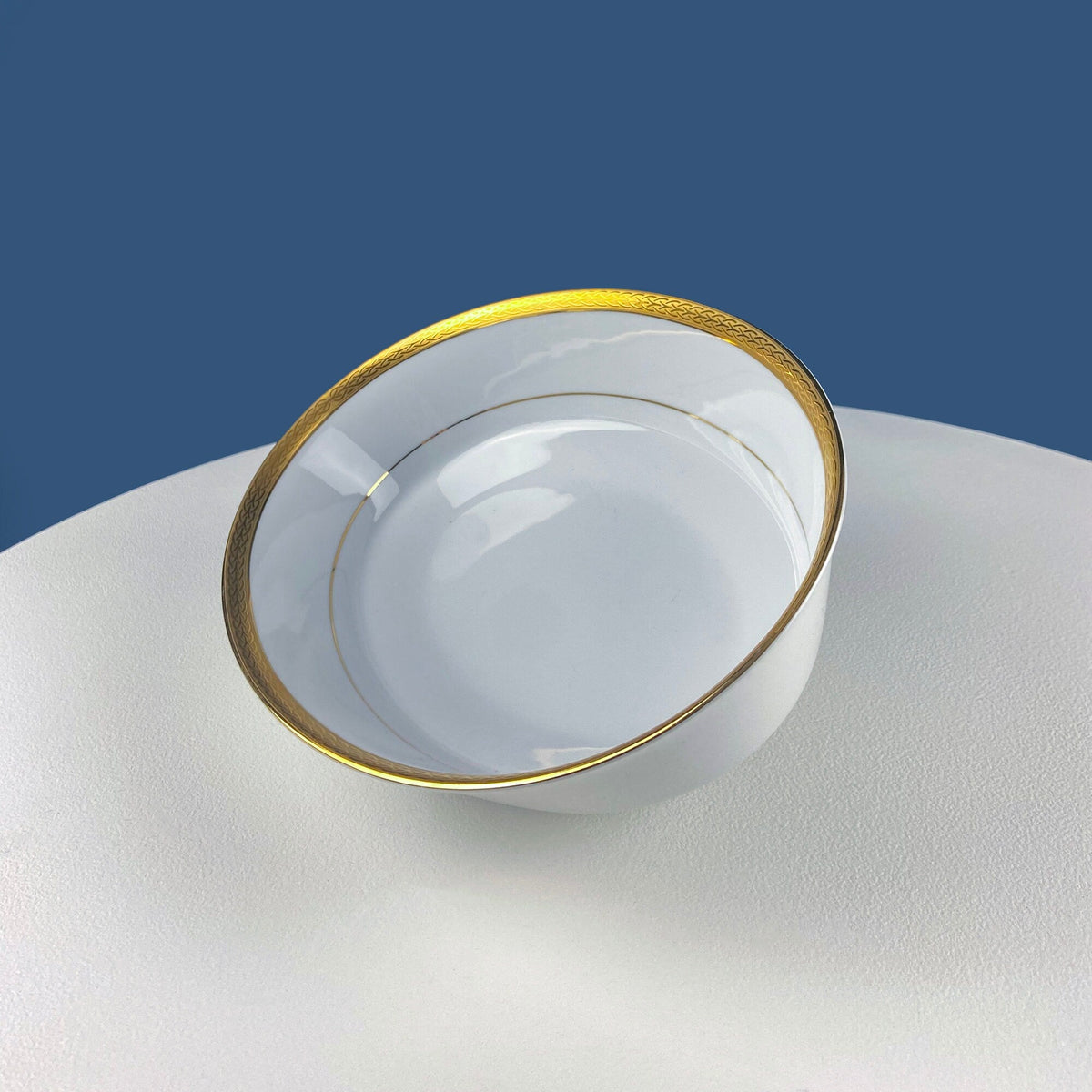 White porcelain oval serving bowl, gold rim, side view