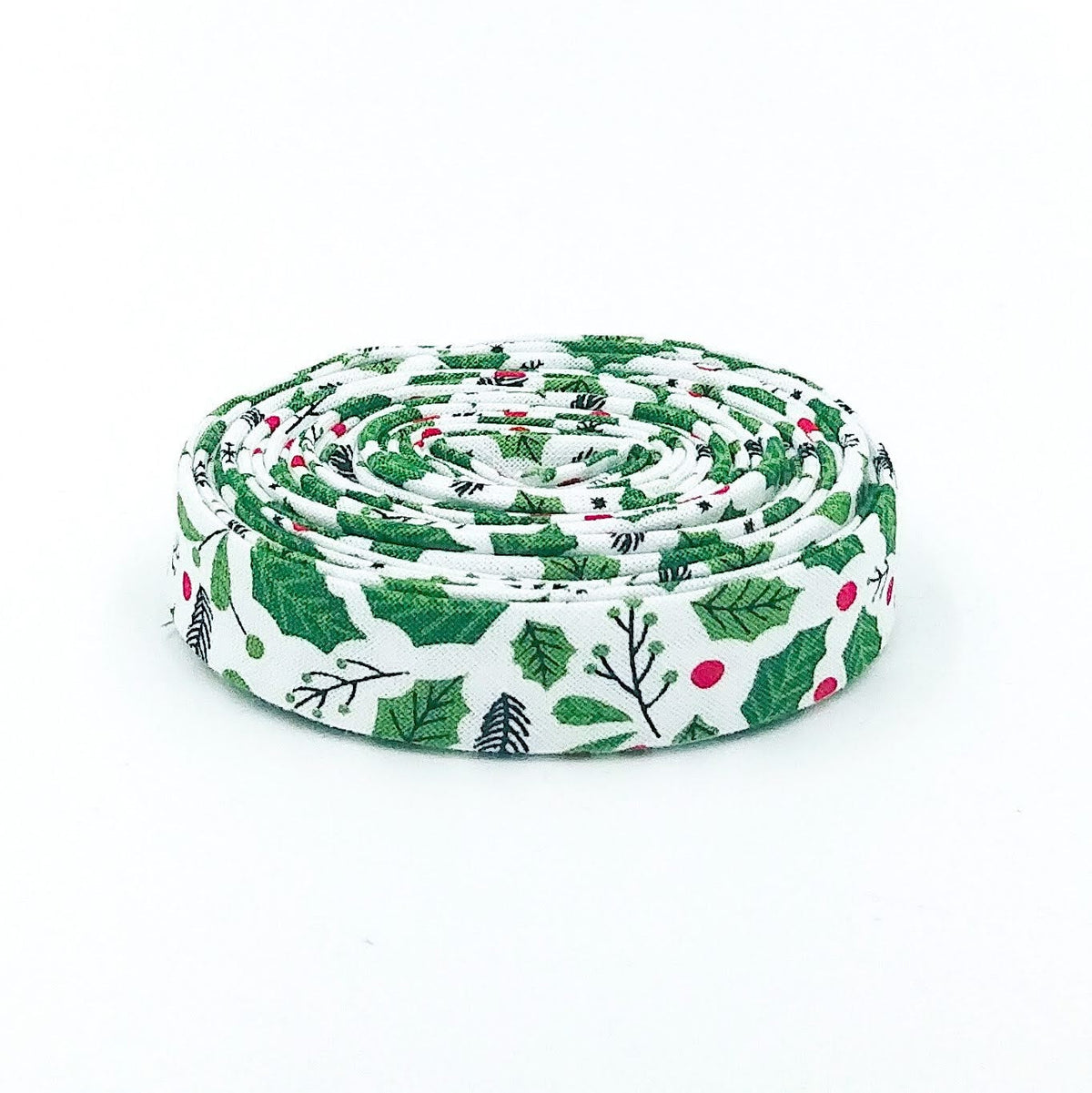 Double-fold 1/2in bias tape in white, green holly and red berry print, tightly coiled roll