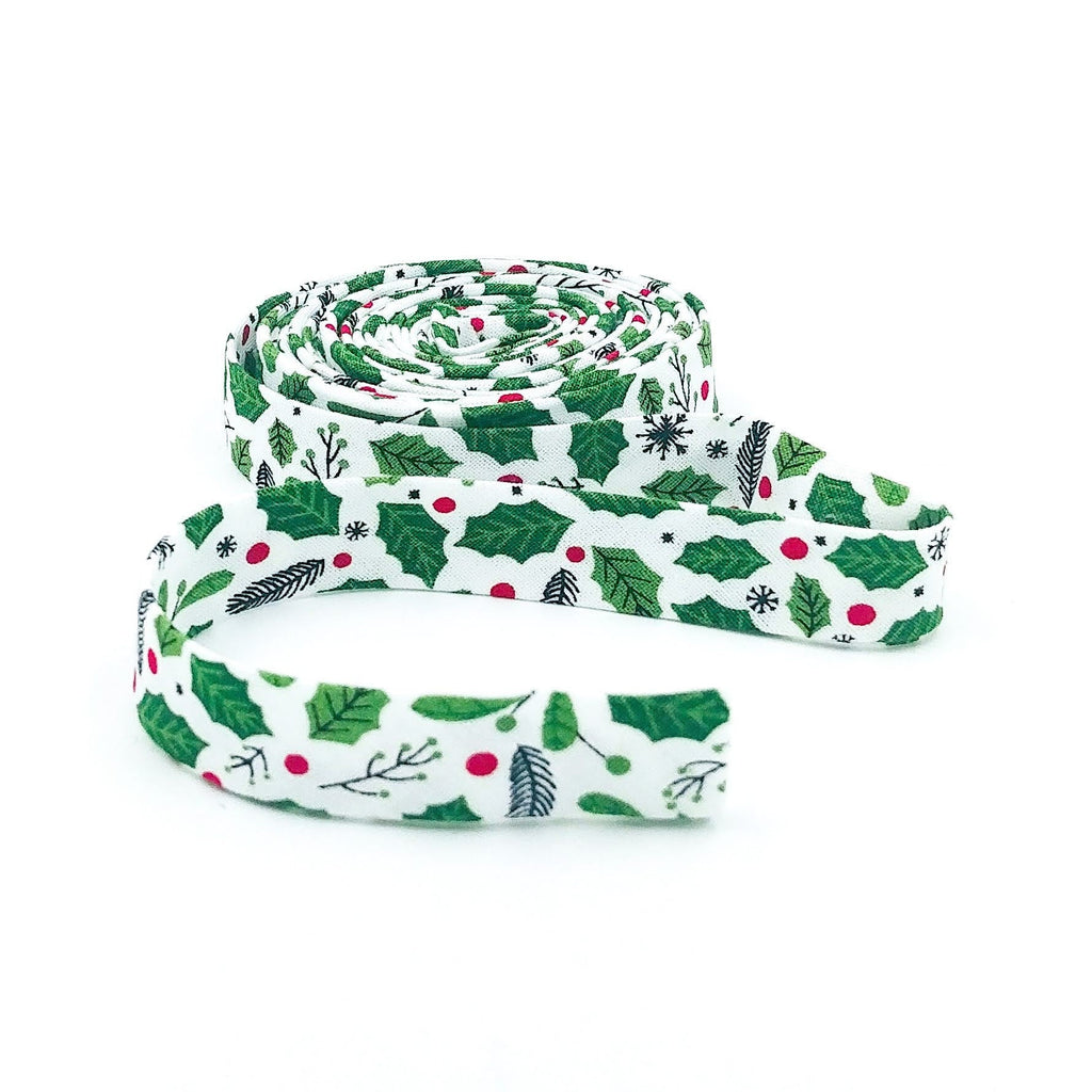 Double-fold 1/2in bias tape, white with green holly leaves and red berries, coiled roll
