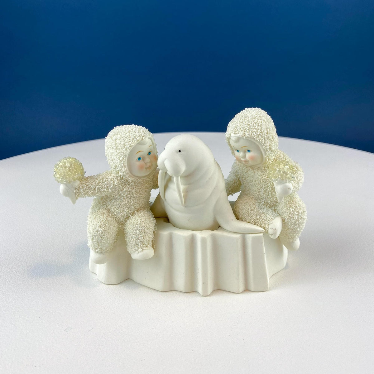 White porcelain figurine with two fuzzy snowbabies and a seated central animal