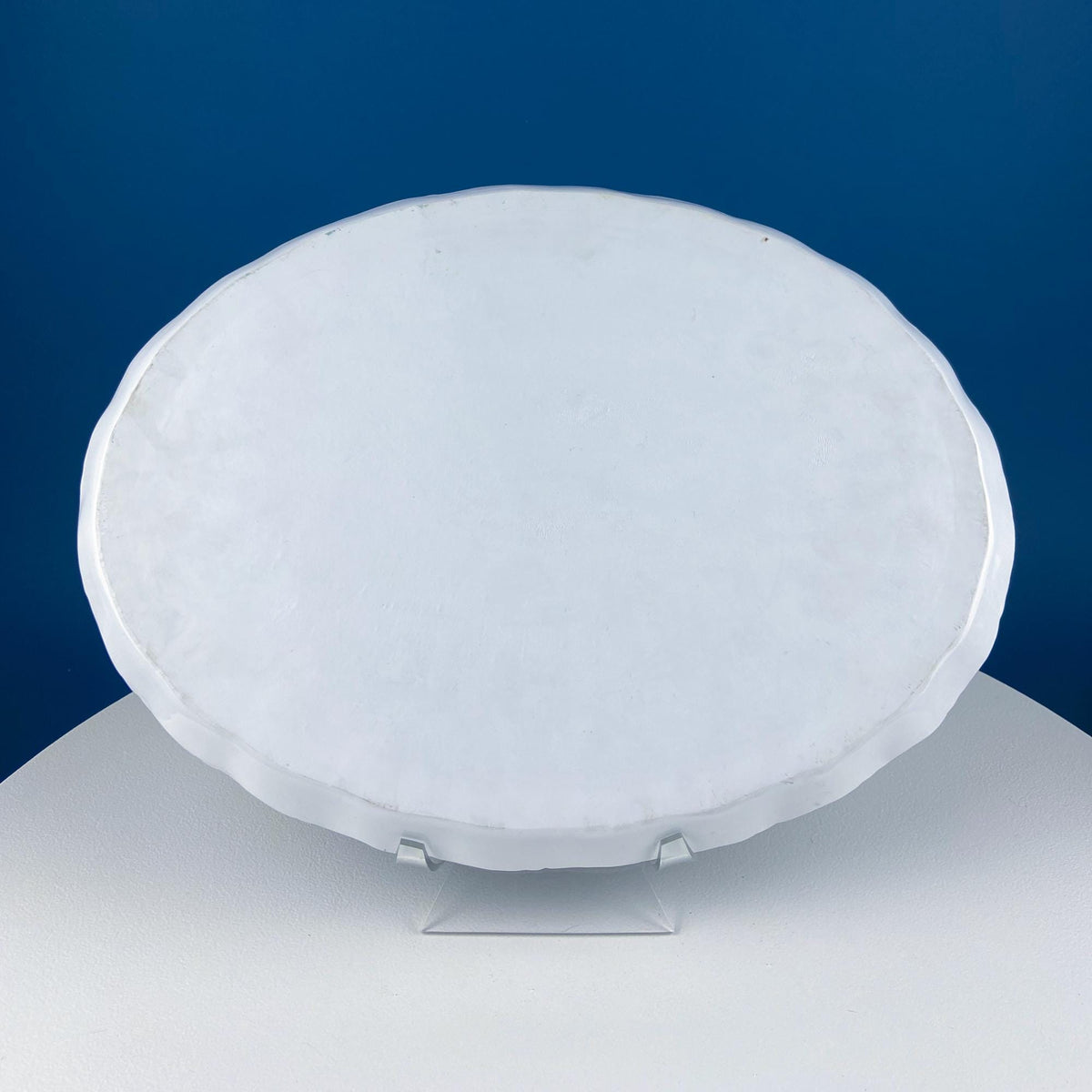 Underside of oval porcelain serving tray, smooth white surface