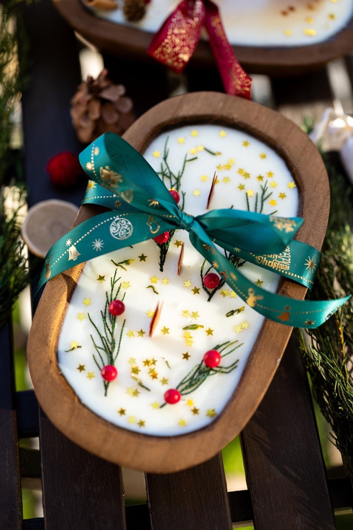 Wood dough bowl candle with white wax, holiday sprigs, and teal ribbon bow