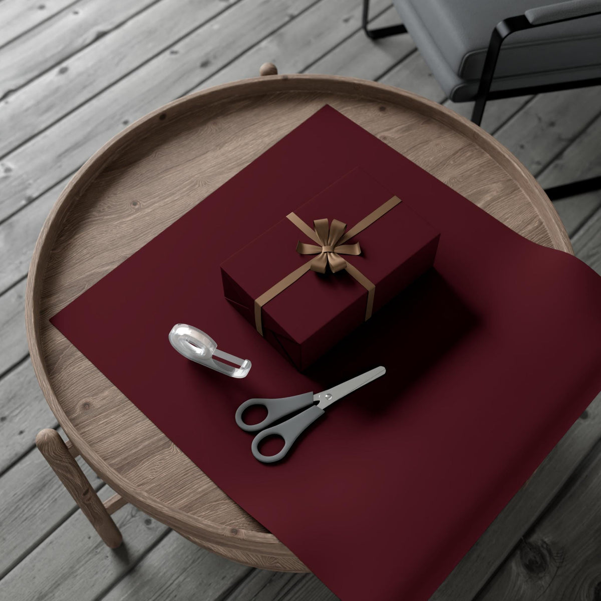 Burgundy wrapping paper on a wooden tray with small gift, tag, tongs, and scissors