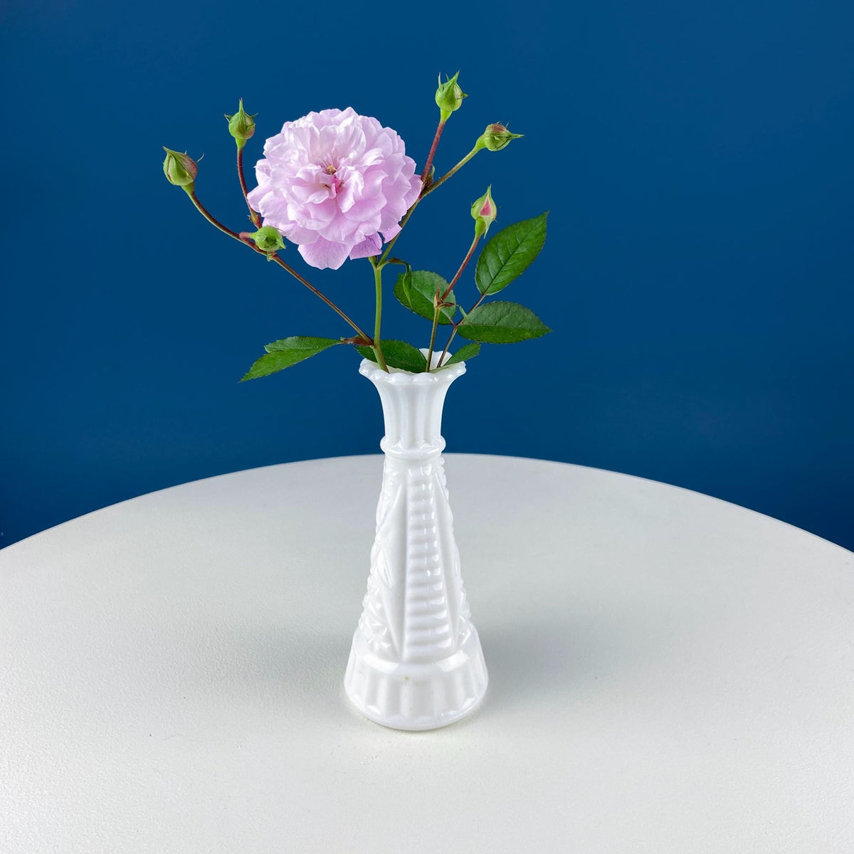 White pedestal vase centerpiece holding pink flower bouquet for serving display