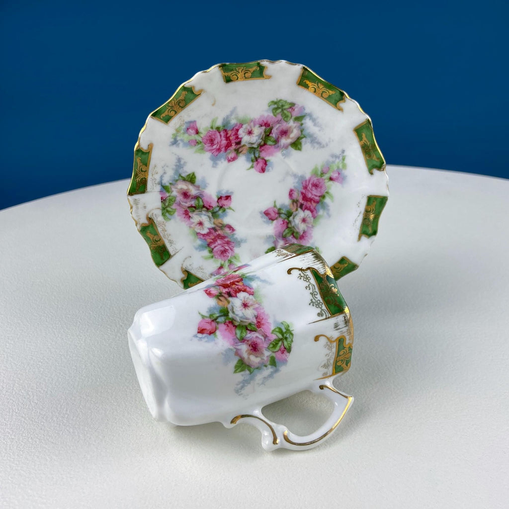 Rose-pattern porcelain cup pair on oval tray with green-gold edging and pink blooms
