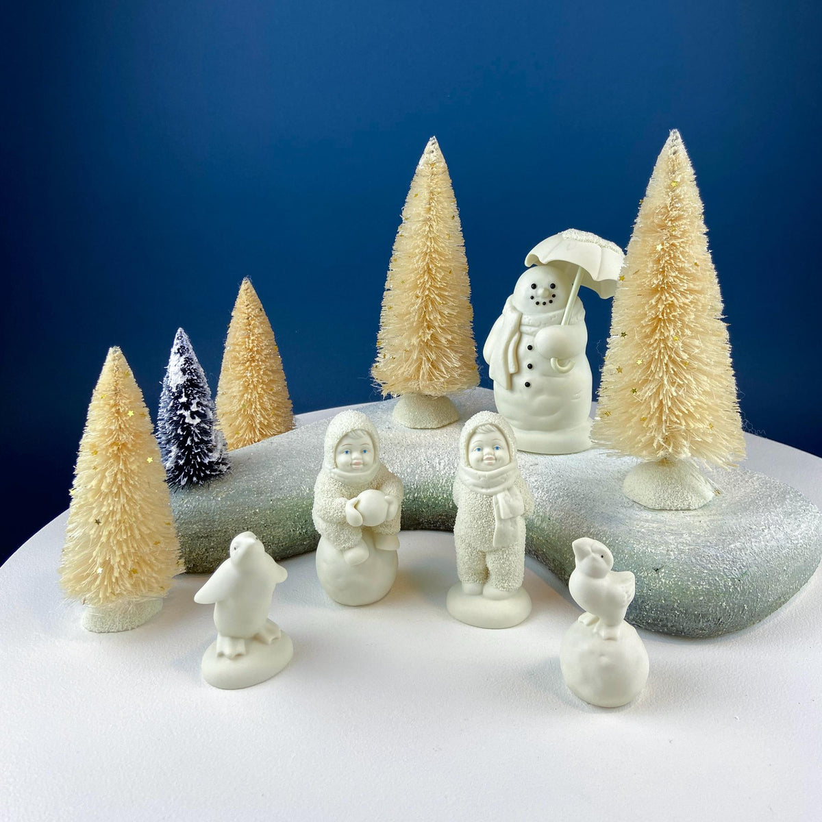 White porcelain figurine set with snowman, birds, and smiling children