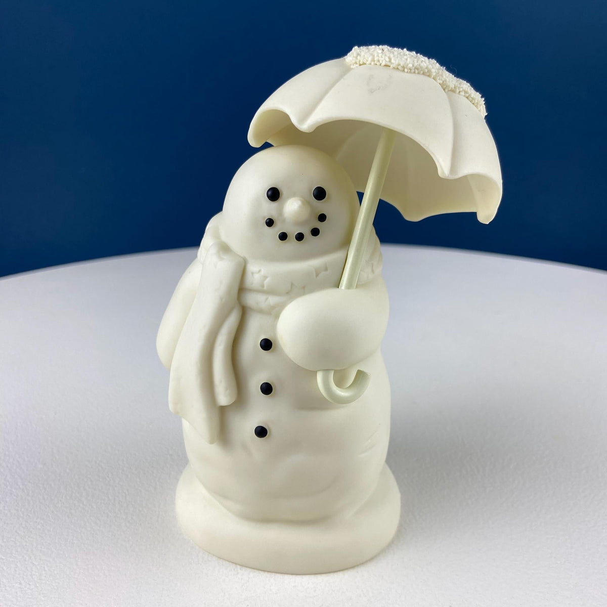 White porcelain snowman figurine under umbrella with bird and snow motif