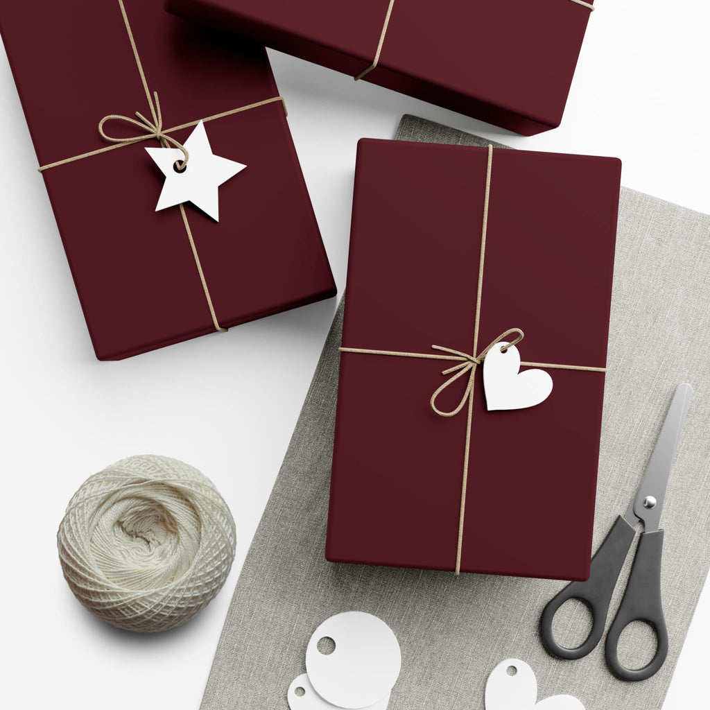 Burgundy wrapping paper sheets with gold strings, star tag, bow and scissors
