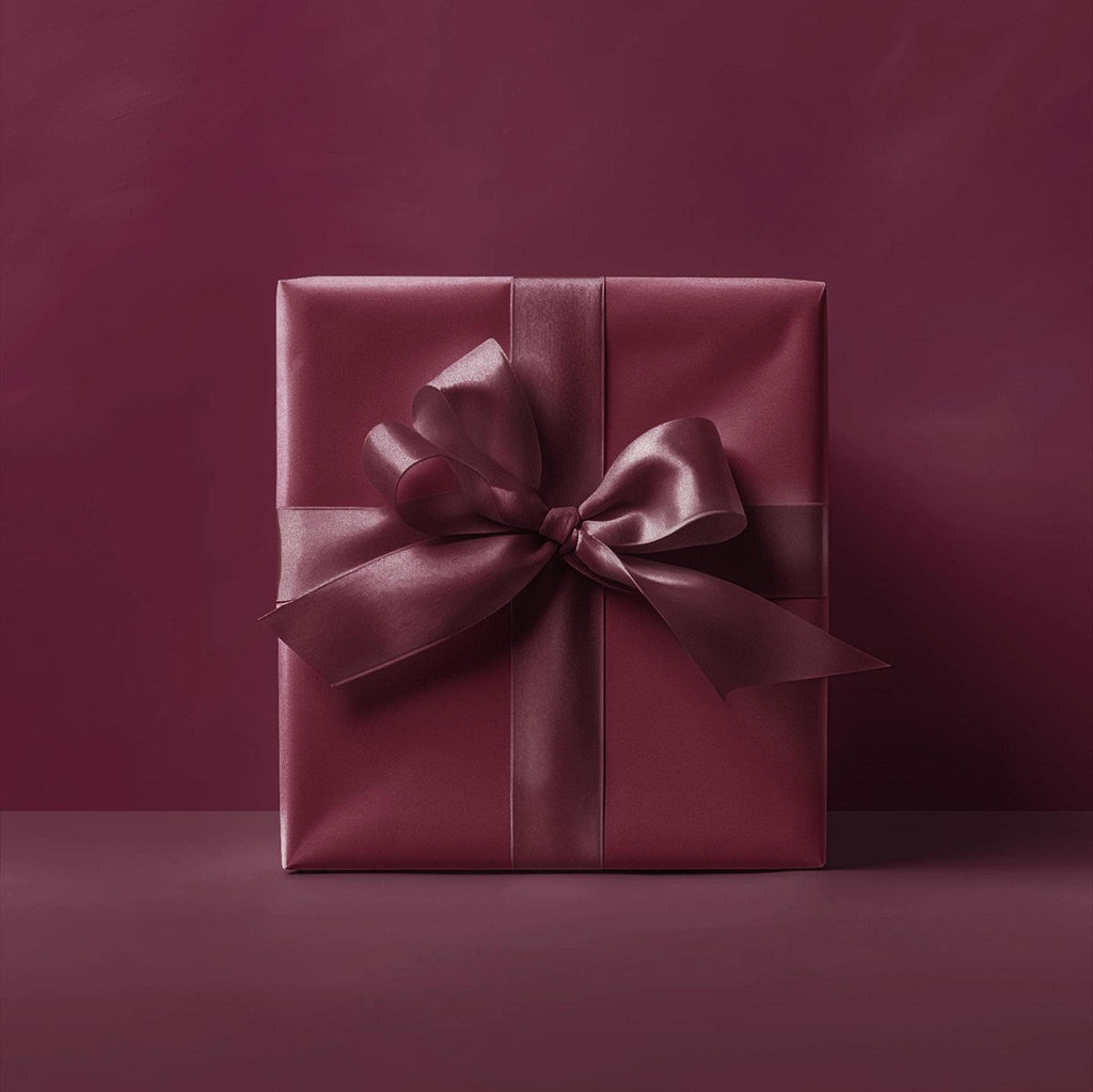 Burgundy gift box wrapped in solid wrapping paper with satin bow and ribbon