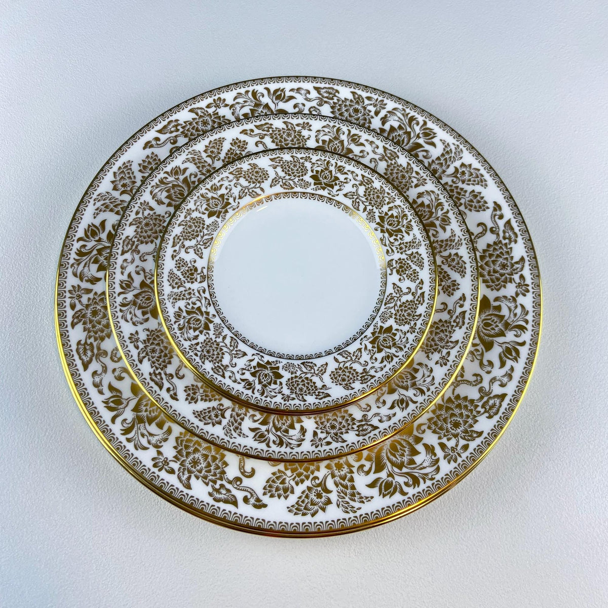 Porcelain plate with gold damask ring and ornate floral scroll border