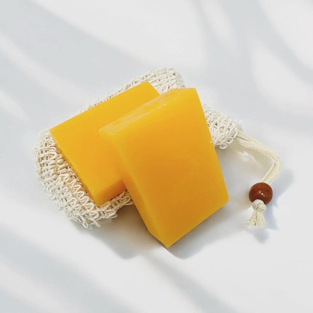 Orange-yellow soap bars in a white mesh pouch with a wooden bead pull