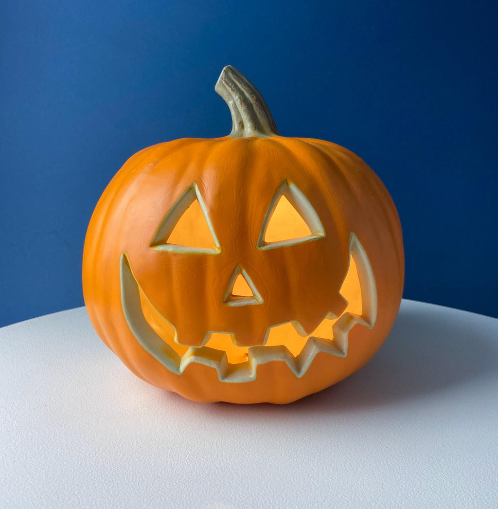 Orange jack-o’-lantern lantern decoration with triangular eyes and wavy mouth