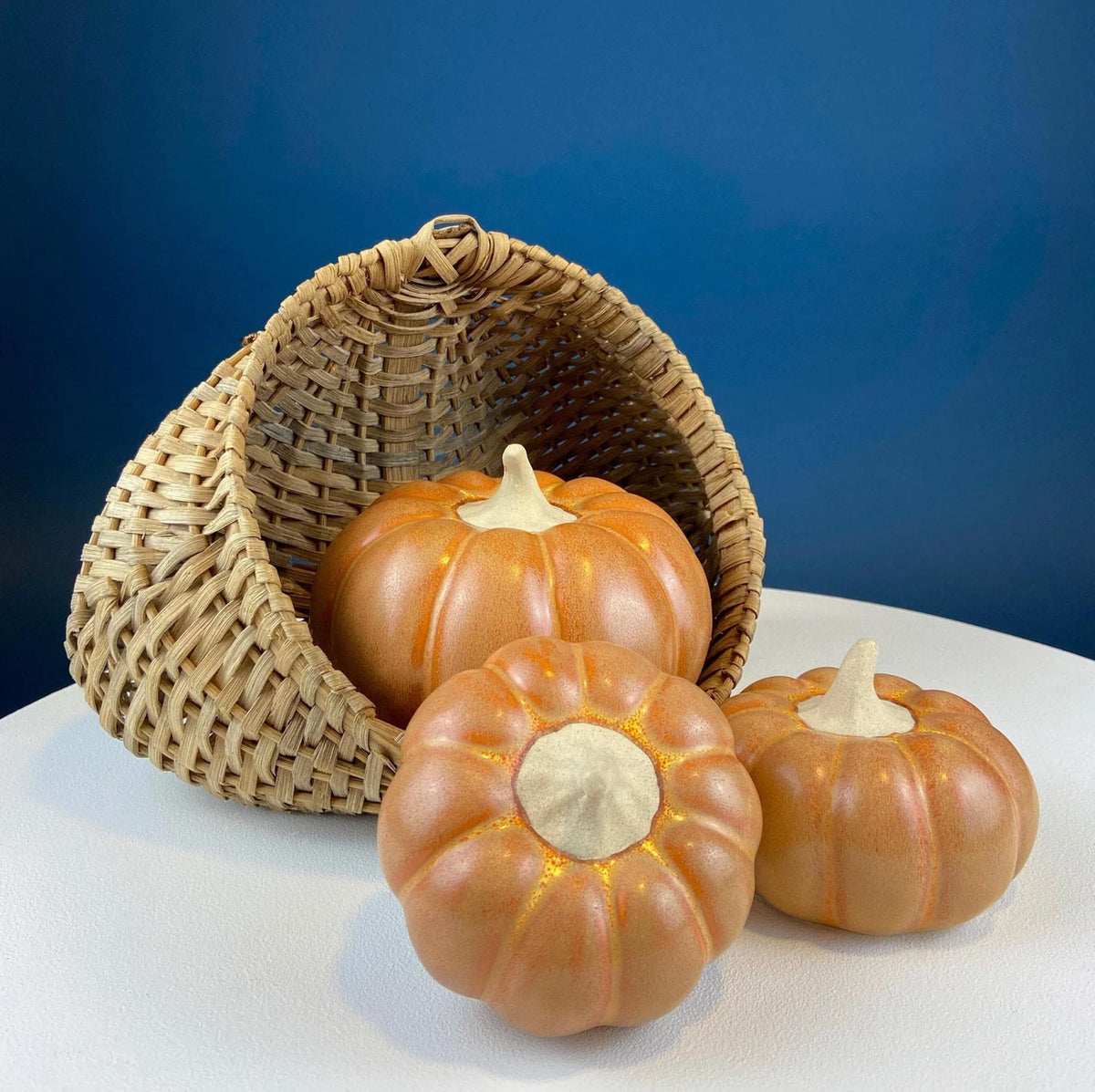 Rattan basket with orange pumpkin-shaped lights on white tabletop