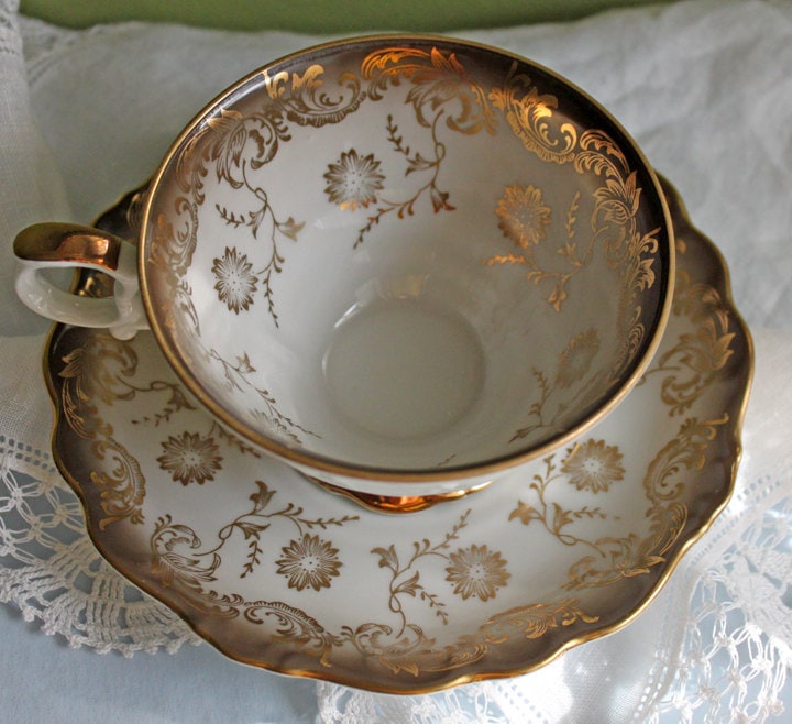 White porcelain tea cup and saucer with gold trim and ornate floral pattern