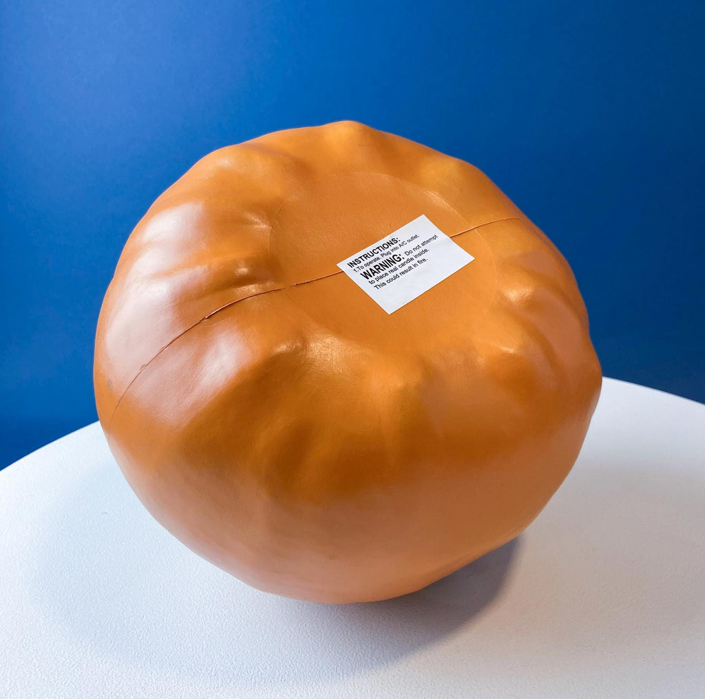 Orange pumpkin lantern back view with white warning label sticker