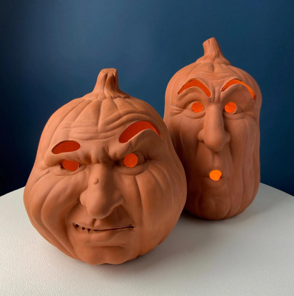 Two orange pumpkin lantern decorations with carved faces and glowing eyes