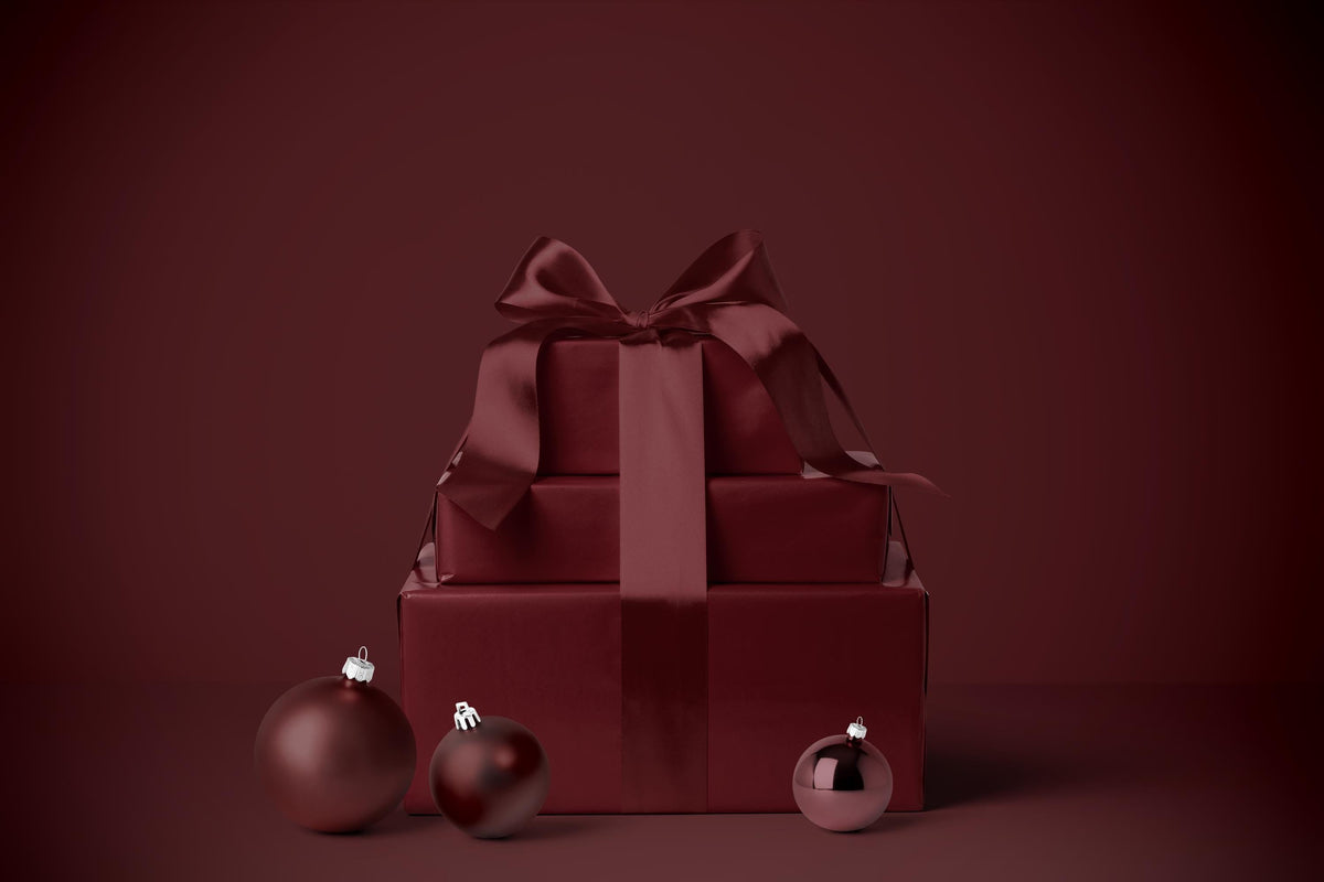 Burgundy gift wrapping paper with satin-style ribbon bow on a wrapped box