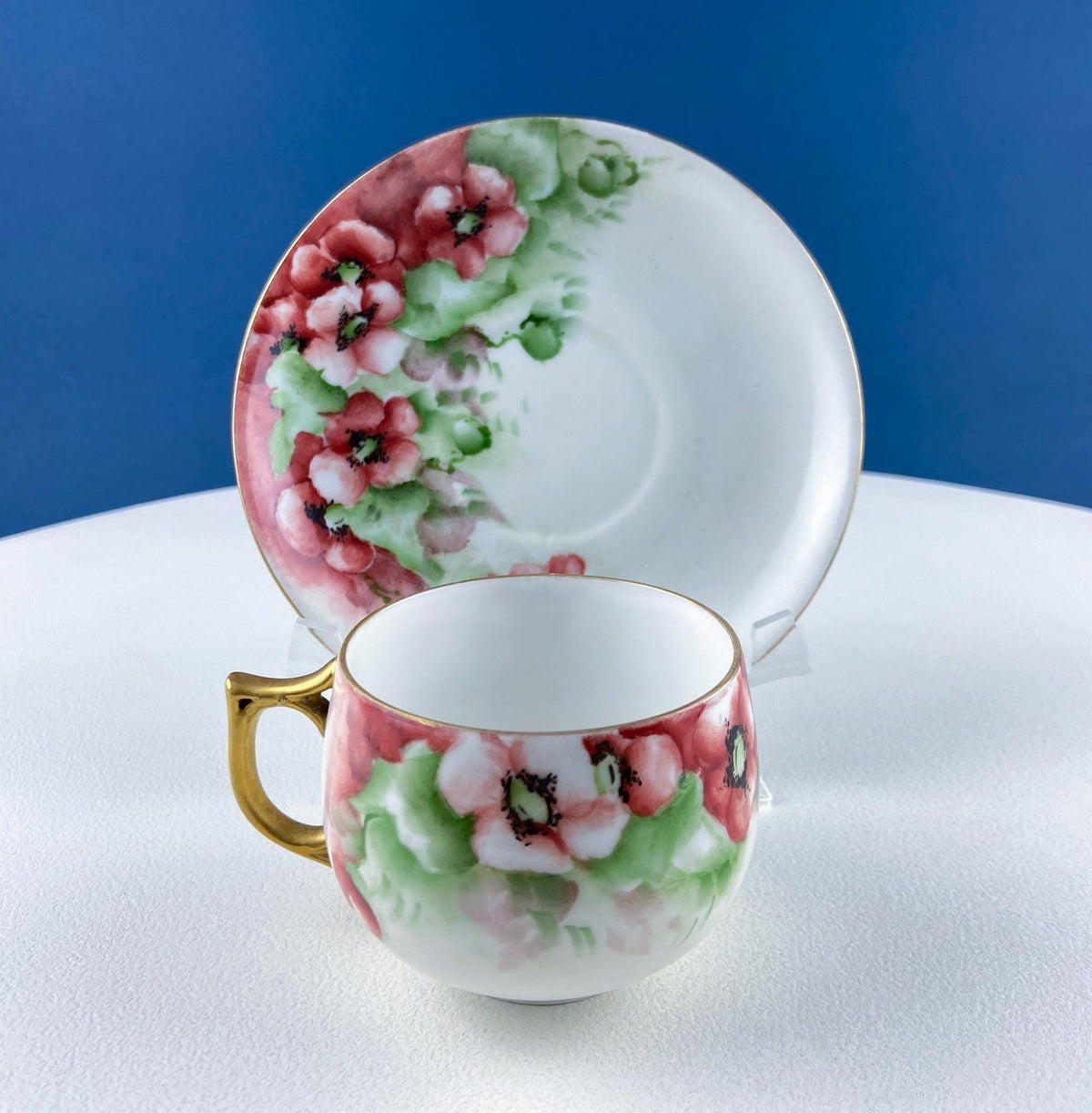 Porcelain tea cup and saucer with pink berry floral pattern and green accents
