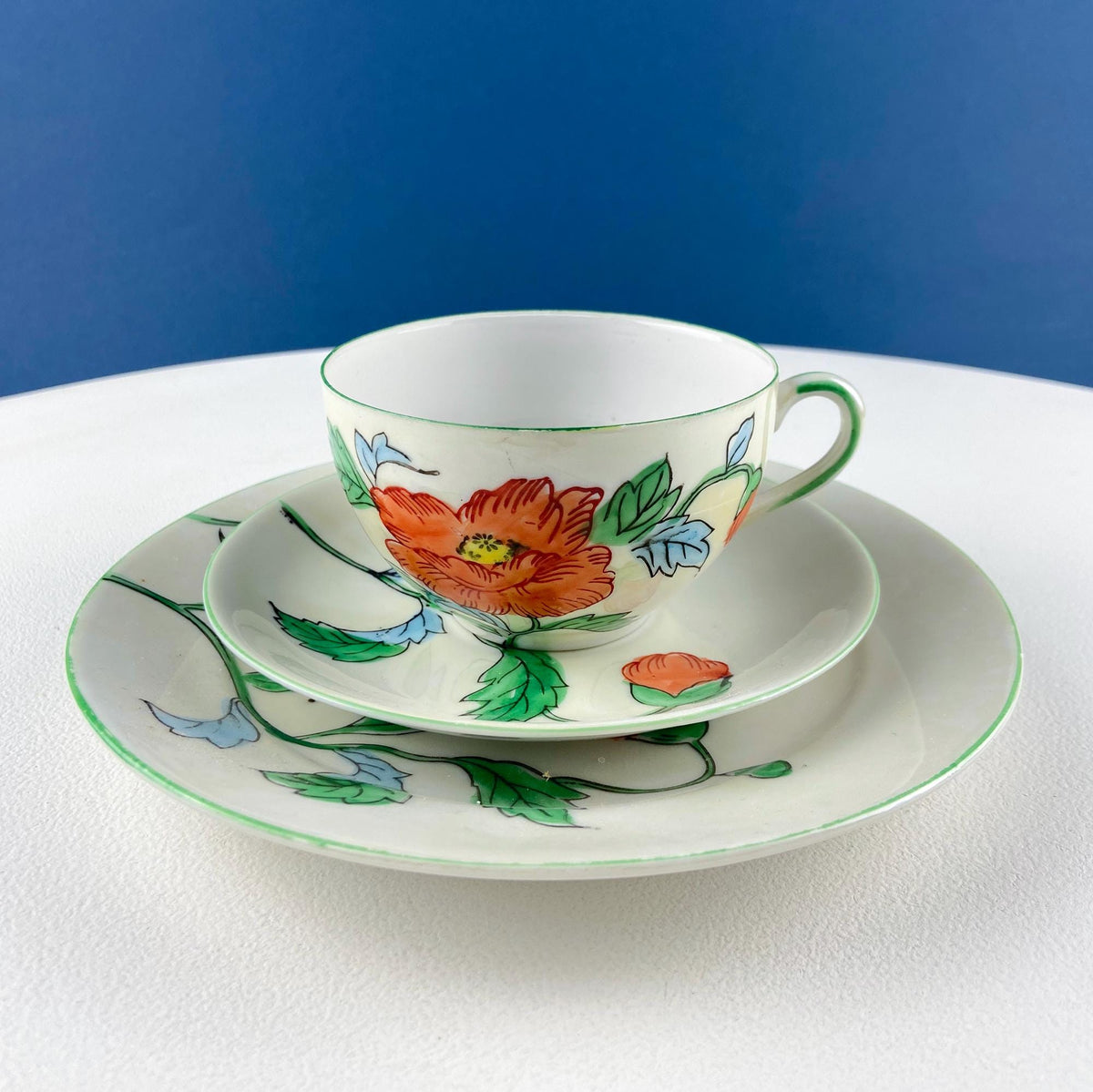 Porcelain tea cup and saucer with orange flower design and green-blue leaves