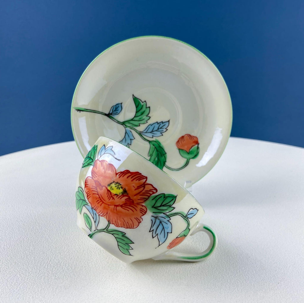 Porcelain tea cup with orange flowers and blue-green leaves, curved handle
