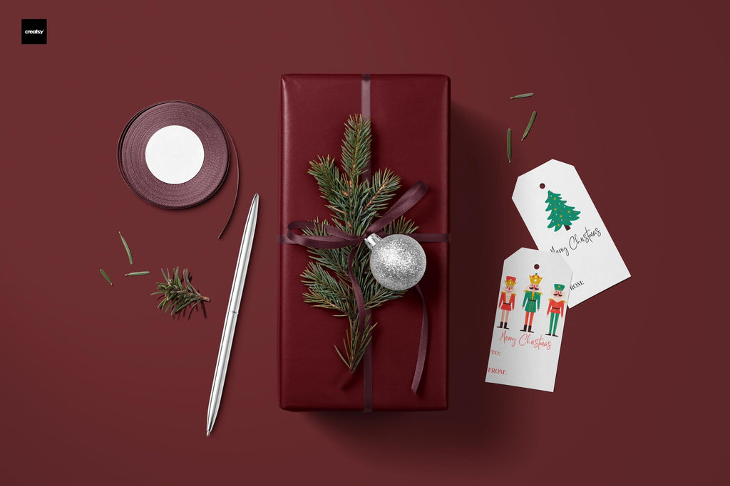 Burgundy wrapping paper bundle with greenery, ornaments, ribbon, and gift tag