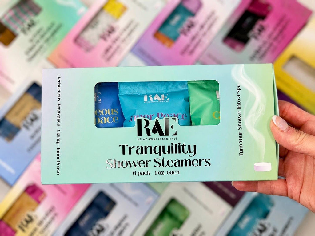 Tranquility 6-pack shower steamers box held in hand, with four colored sachets window