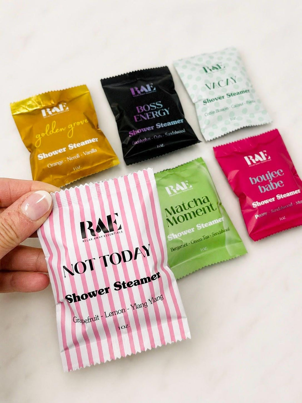 Assorted shower steamer packets in hand, various colors with 'Not Today' labels