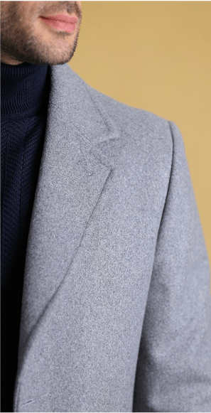 Light-gray overcoat shoulder and lapel detail over dark knit.