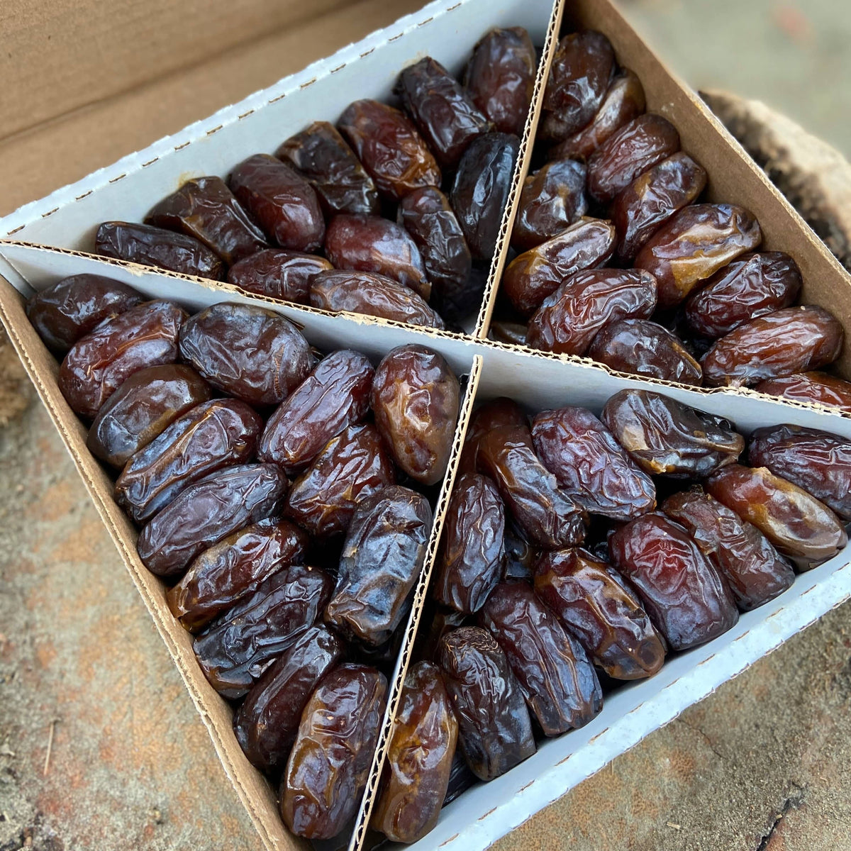 Soft Medjool dates in a two-compartment cardboard box, close-up of dark red dates