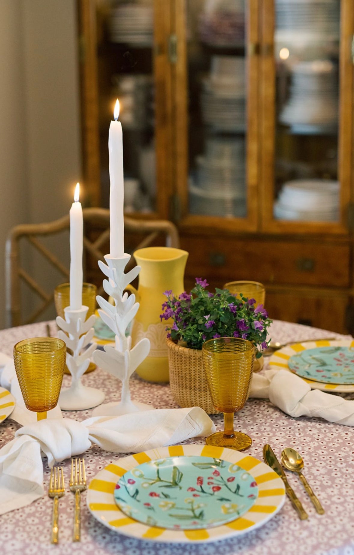 Botanical china plate with yellow rim on table with candles and glassware